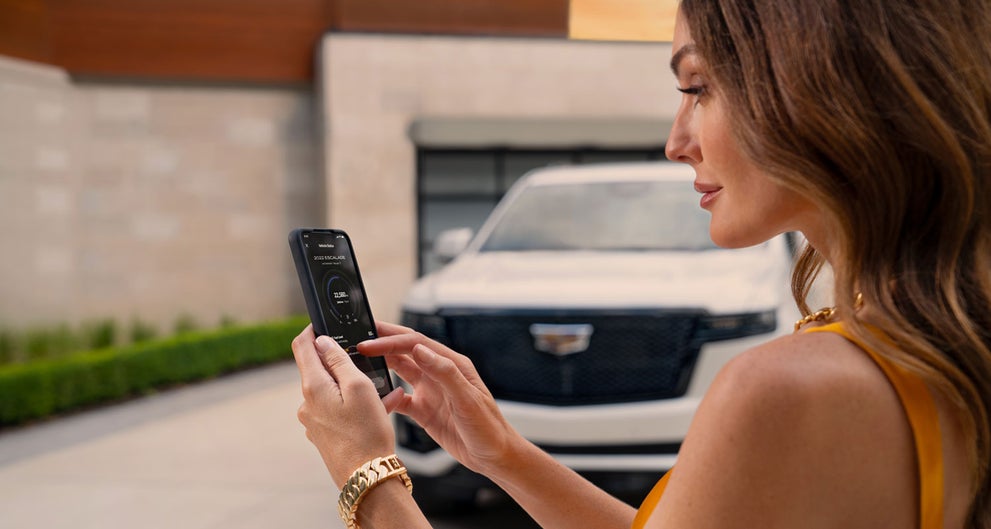 lady checking her mobile with a Cadillac vehicle background | Crestview Cadillac of West Covina in West Covina CA
